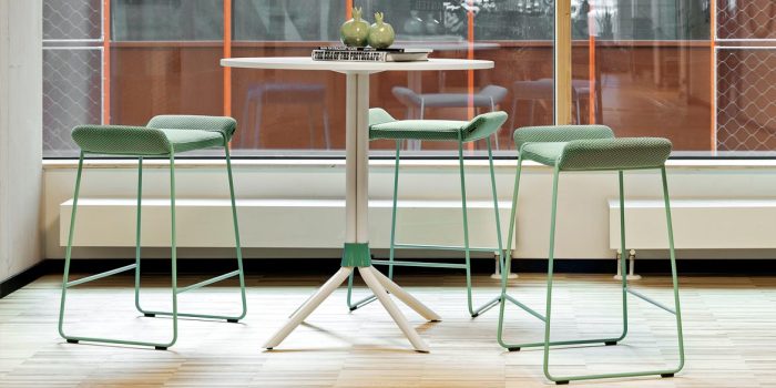 Commercial stool with a green fabric seat pad