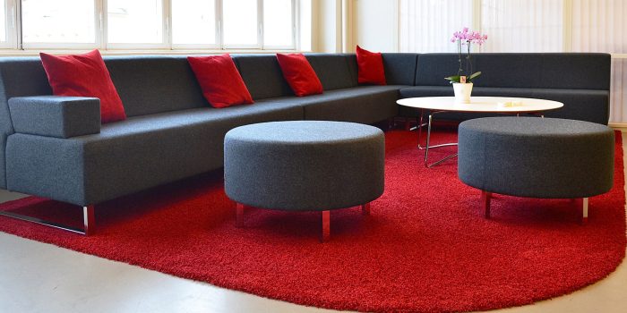 Large grey corner office sofa with red cushions